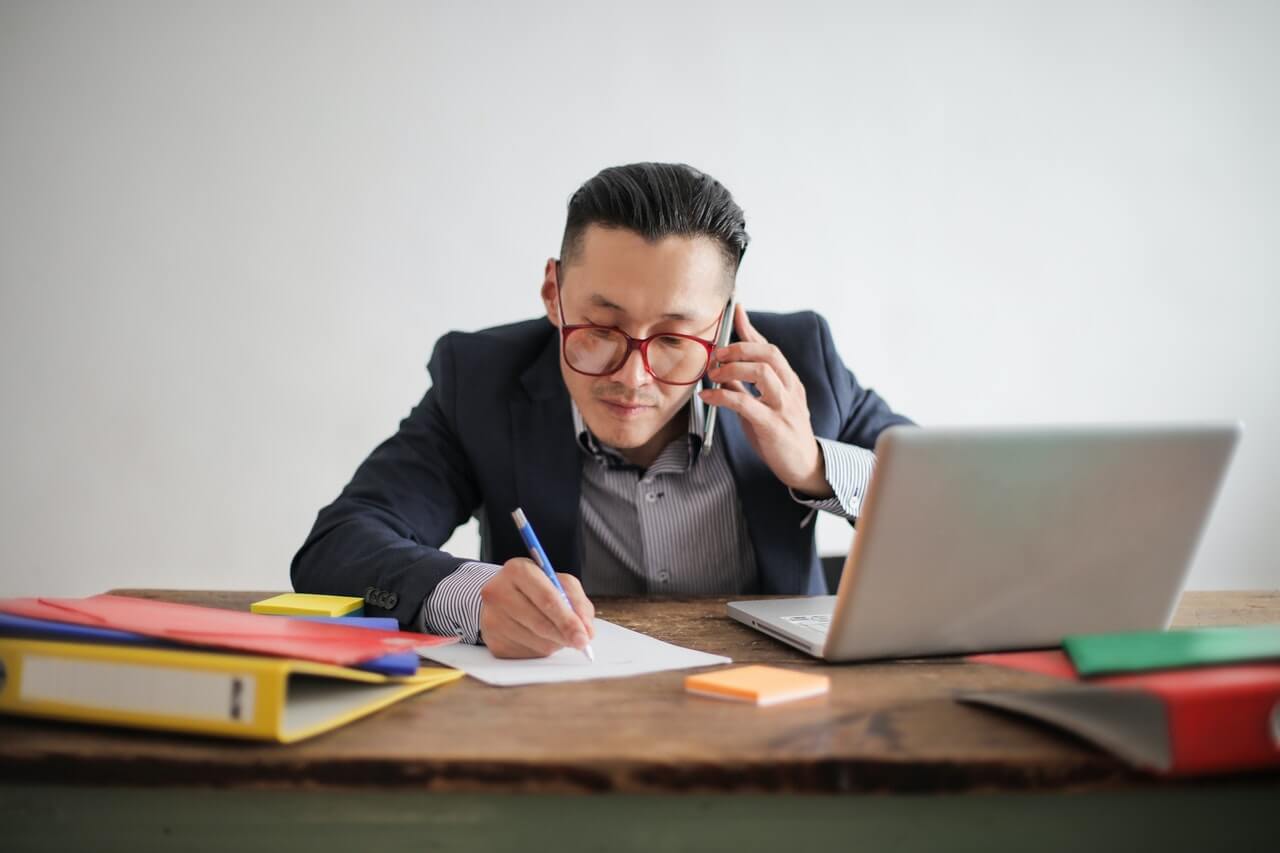 man on the phone and writing on paper